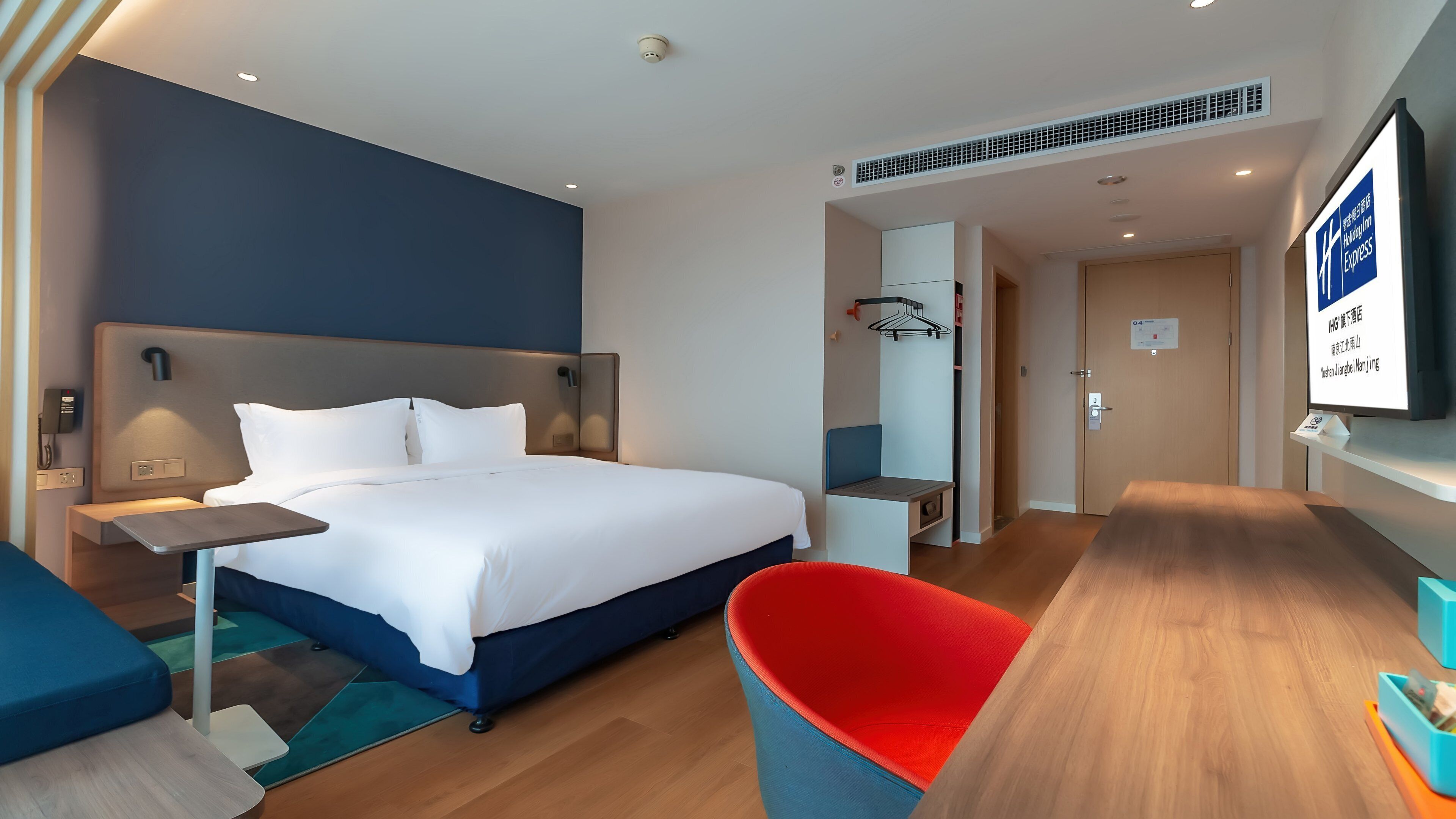 A hotel room with a bed, bedside table, and a TV.