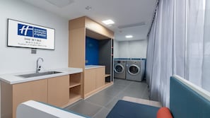 A hotel room with a sink, a washing machine, and a bed.