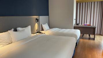 A hotel room with two beds, a desk, and a nightstand.