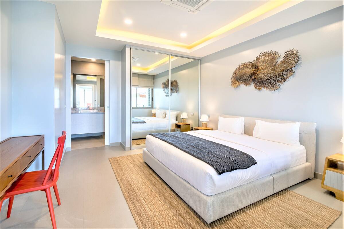 A modern bedroom with a large bed, a desk, and a chair.