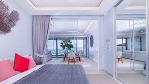 A modern bedroom with a large bed, a dining area with a view, and a sliding glass door leading to a balcony. - Andamaya Surin Bay (Choeng Thale)