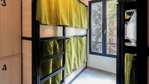 A room with a bunk bed, a window with a view of trees and buildings, and a door with a number on it. - Paris Hostel (Paris)
