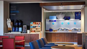 A modern cafe with seating, a coffee station, and a breakfast bar.
