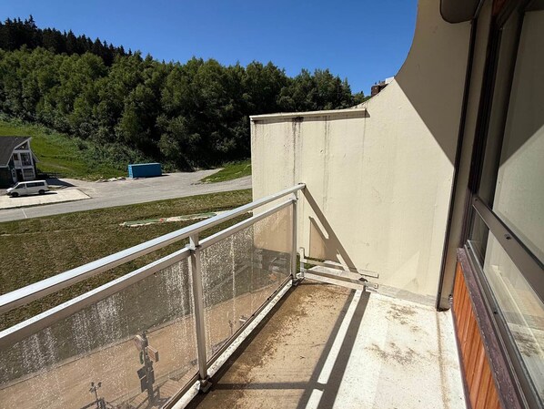 En balkong med ett metallräcke som vetter ut mot en parkeringsplats och en byggnad med ett sluttande tak.