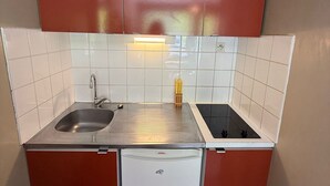 A compact kitchen with a sink, stove, and a small refrigerator.