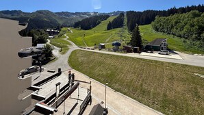 A mountain resort with a ski lift, a parking area, and a view of the surrounding hills.