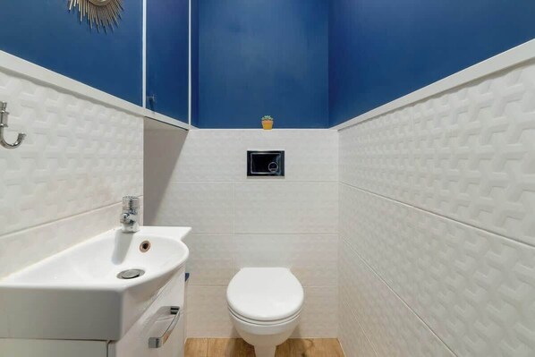A small bathroom with a white sink, toilet, and a small potted plant on the wall. - Family Apartment with Balcony | Close to Malta Lake (Poznan)