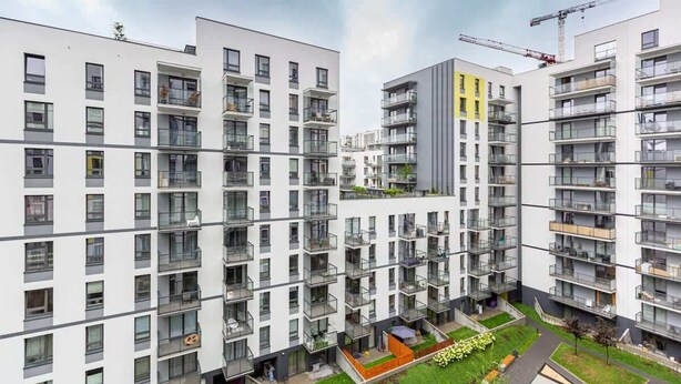 A modern apartment complex with multiple floors, balconies, and a central courtyard.