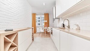A modern kitchen with white cabinetry, a wooden countertop, and a dining area with a table and chairs.