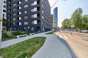 A modern building with a grid of windows, a paved walkway, and a grassy area.