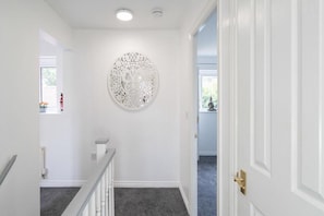 Stylish hallway with a circular art piece and carpeted floor.