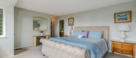 A bedroom with a large bed, a nightstand, a dresser, a mirror, and a painting on the wall.