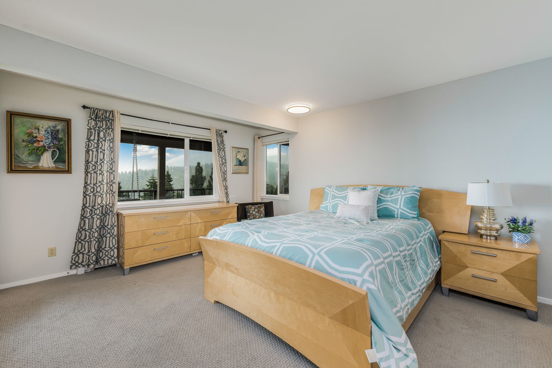 A bedroom with a bed, bedside table, and a window with curtains.