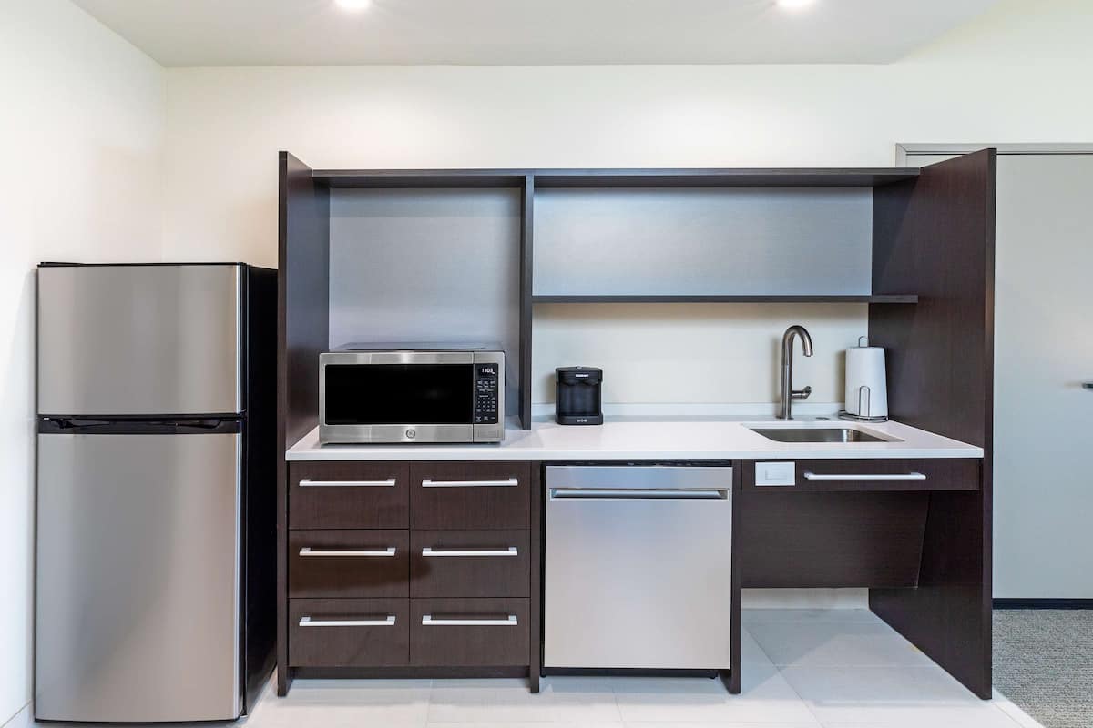 Una cocina compacta equipada con refrigerador, microondas, cafetera y lavavajillas.