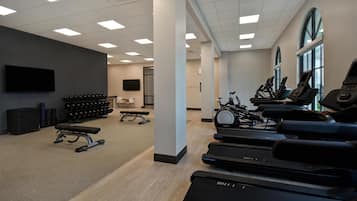 Una sala de gimnàstica amb cintes de córrer, pèses i una banca.