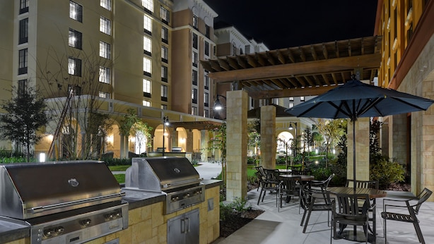 An outdoor patio with a barbecue grill, dining area, and umbrella.