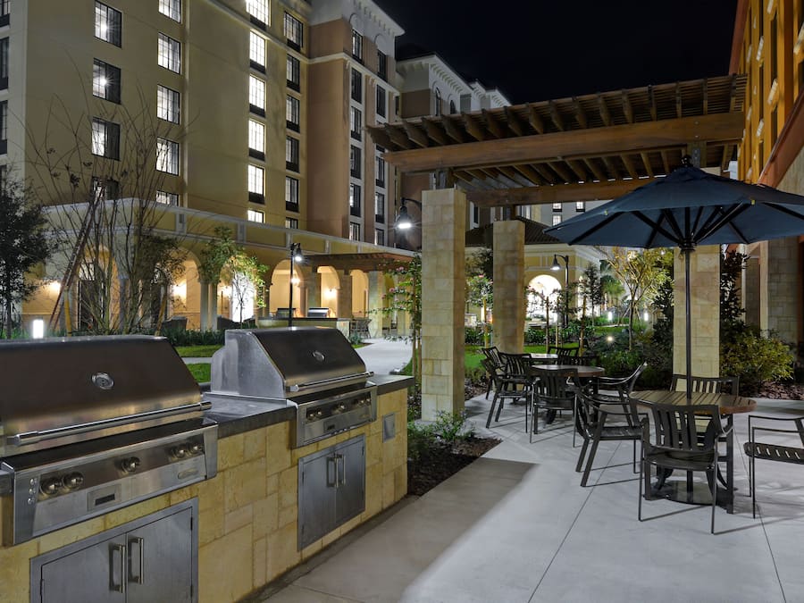 An outdoor patio with a barbecue grill, dining area, and umbrella.