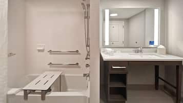 A modern bathroom with a bathtub, shower, and a vanity with a mirror.