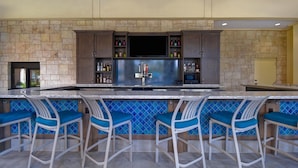 A bar area with a stone wall, a flat-screen TV, and a beer tap.