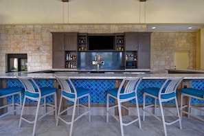 A bar area with a stone wall, a flat-screen TV, and a beer tap.