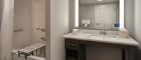 A modern bathroom with a shower, a sink with a mirror, and a towel rack.