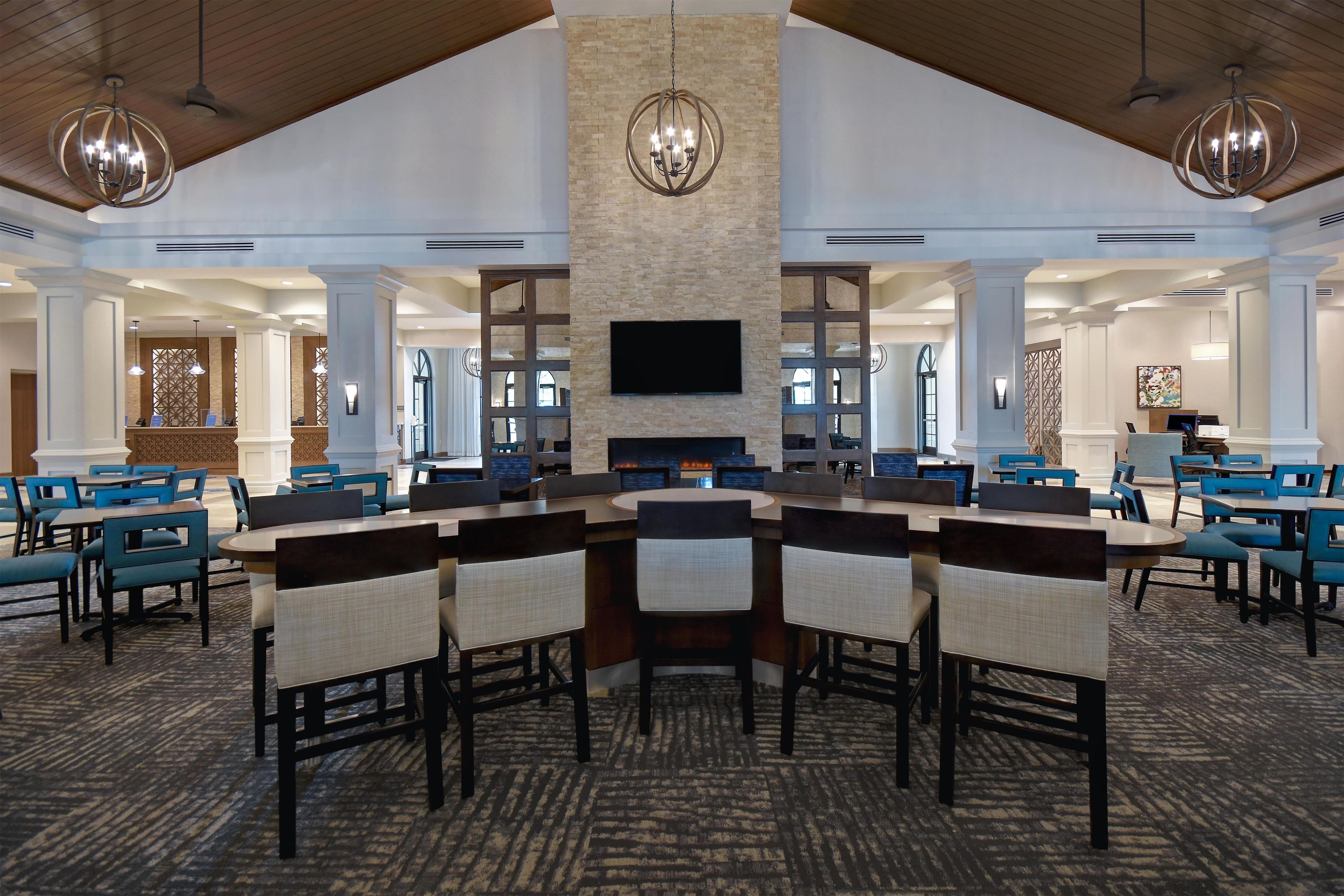 A spacious conference room with a large table surrounded by chairs, a fireplace, and a flat-screen TV mounted on the wall.