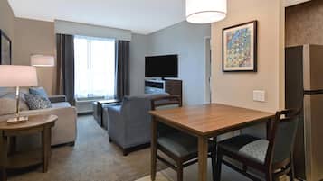 Une chambre d’hôtel équipée d’une table à manger, de chaises, d’un canapé, d’une télévision et d’un réfrigérateur.