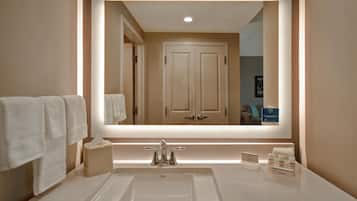 A bathroom with a large mirror, a sink, and a towel rack.