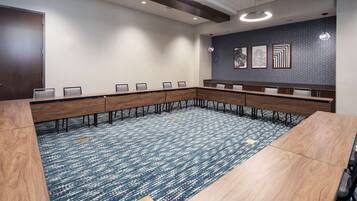 A conference room with a long table, chairs, and a carpeted floor.