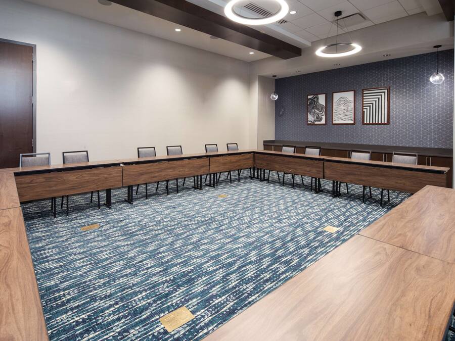 A conference room with a long table, chairs, and a carpeted floor.