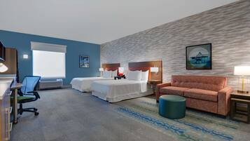 A hotel room with two beds, a desk, a chair, a sofa, and a patterned rug.