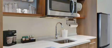 Una cocina moderna con microondas integrado, pileta de acero inoxidable y lavavajillas.
