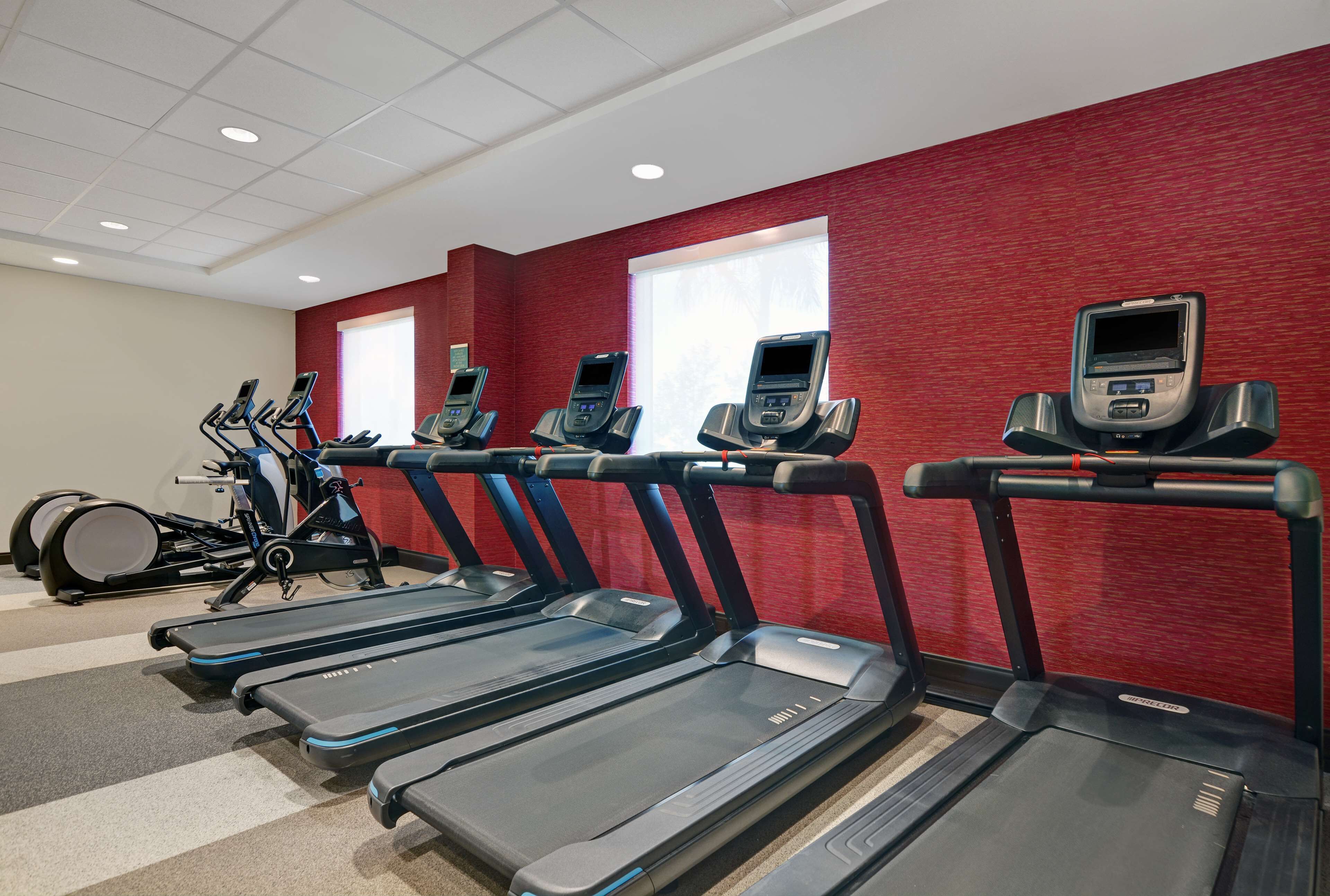 A gym with treadmills, elliptical machines, and a stationary bike.