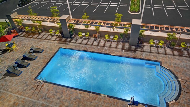 Una piscina en la azotea con sillones de descanso y vista al aparcamiento de abajo.