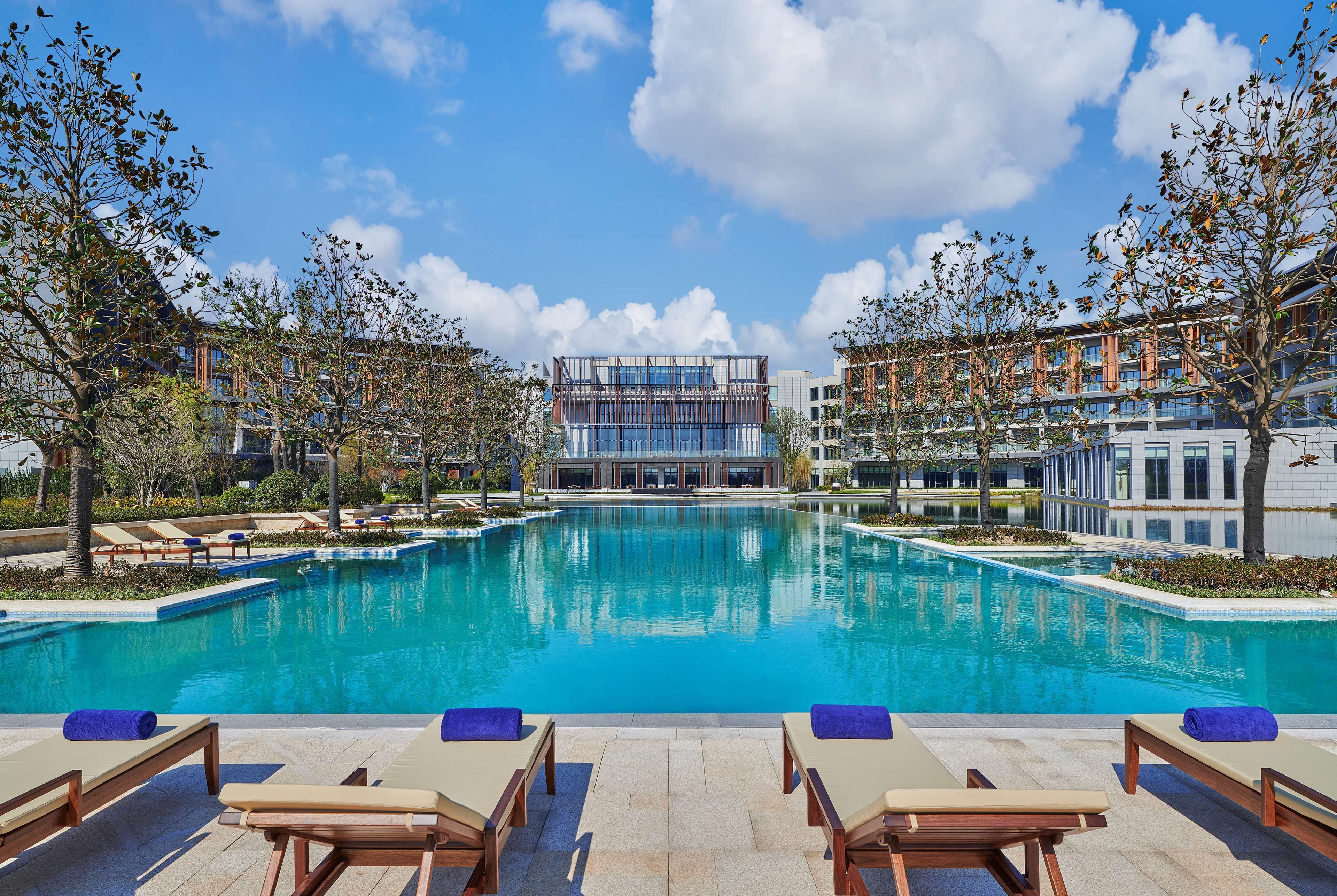 A swimming pool with lounge chairs and a modern building in the background.