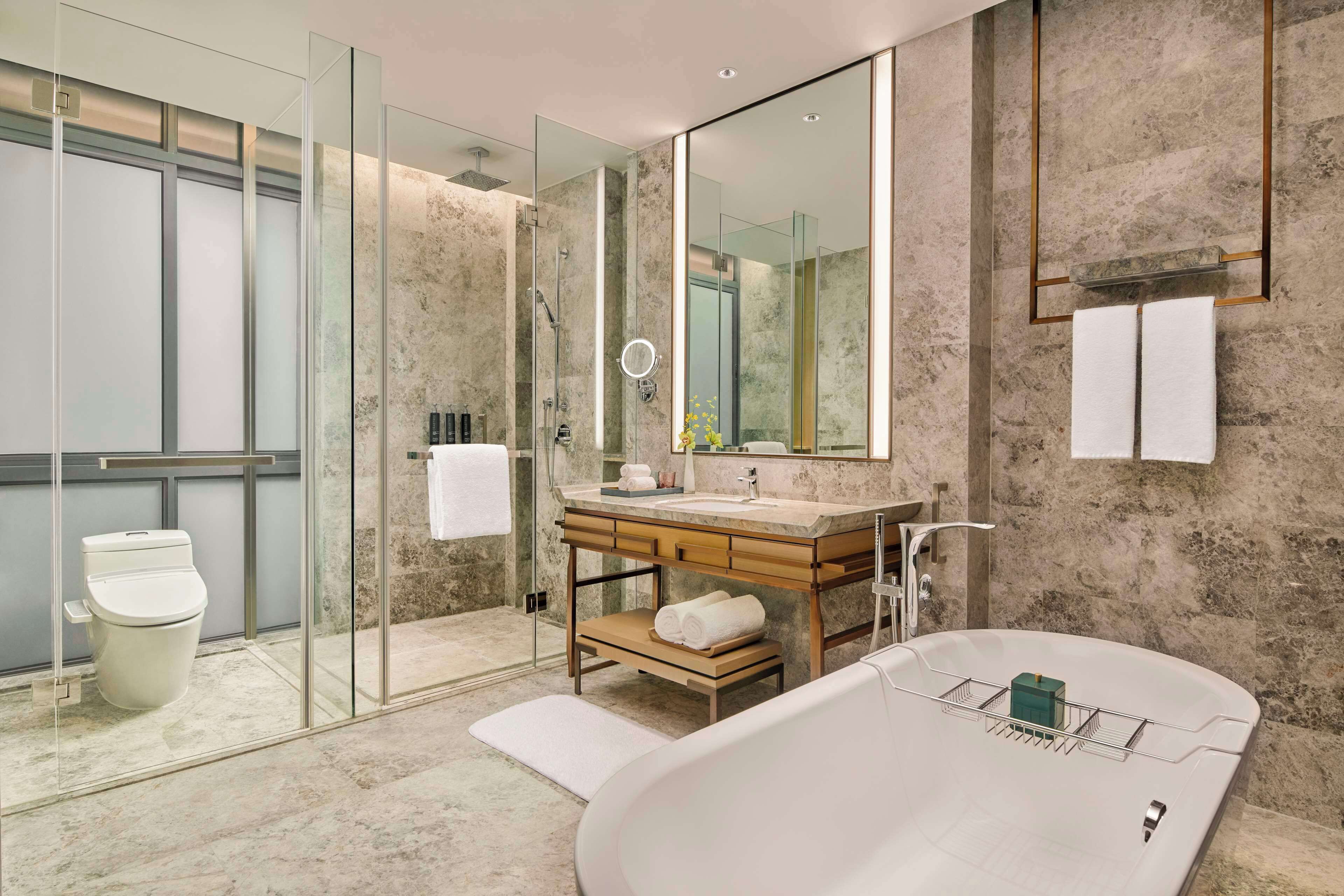 A modern bathroom with a glass-enclosed shower, a freestanding bathtub, and a vanity with a large mirror.