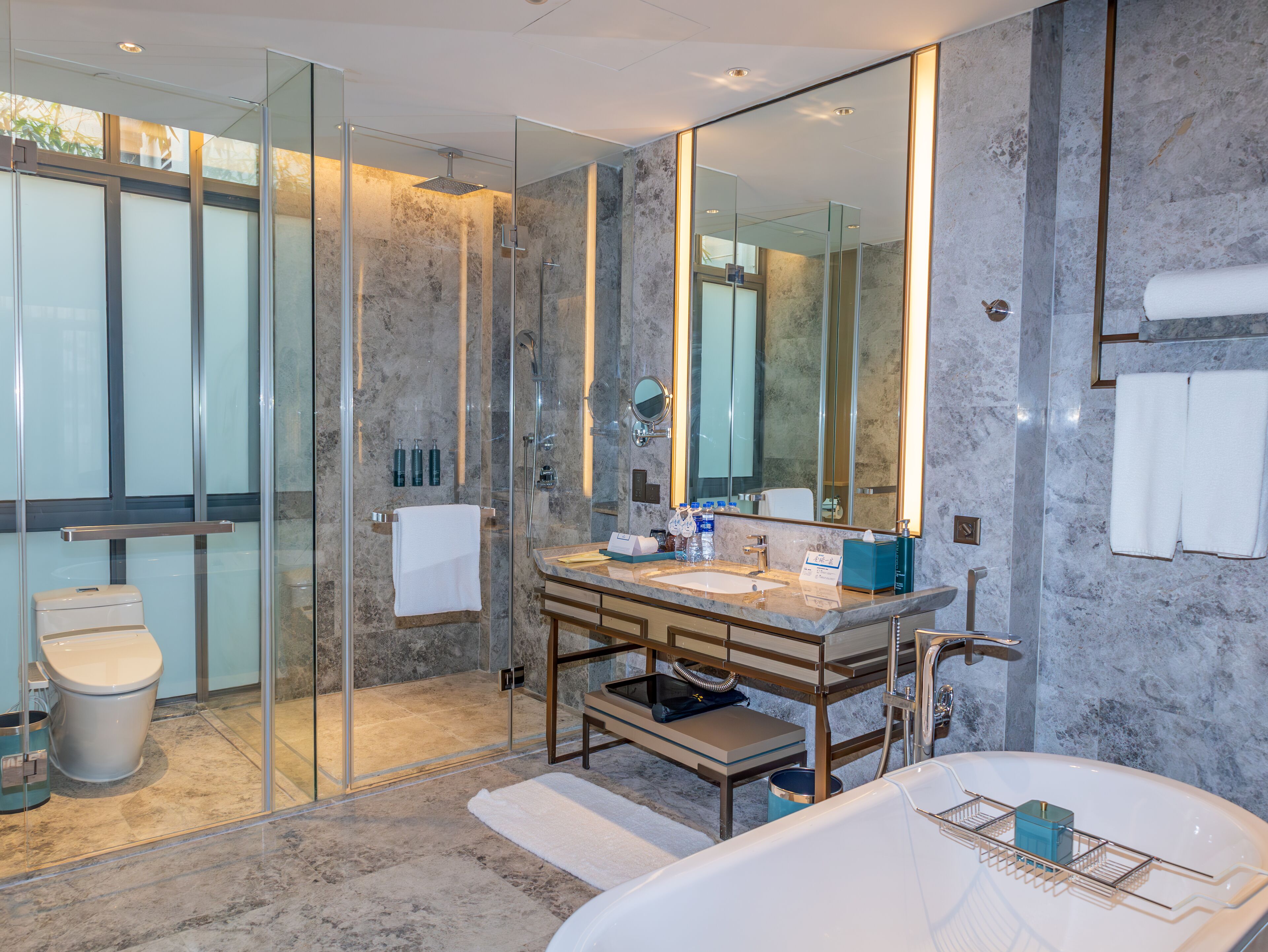A modern bathroom with a glass-enclosed shower, a marble sink, and a large mirror.