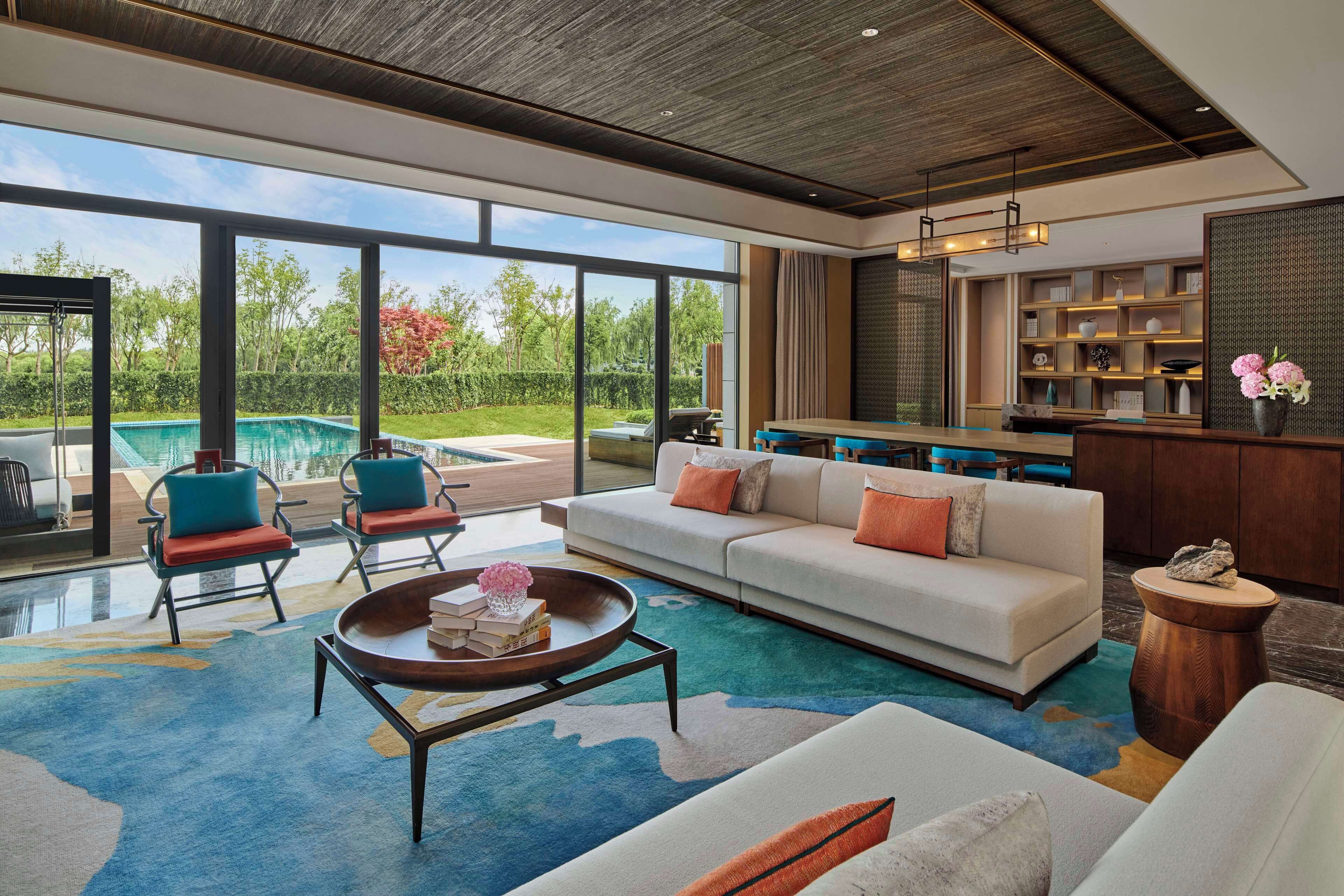 Un amplio espacio de estar con un gran ventanal, una piscina y una cocina moderna.