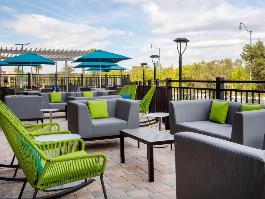 An outdoor patio area with grey sofas, green chairs, and blue umbrellas.