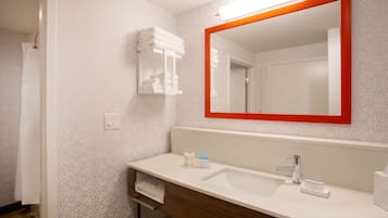 A modern bathroom with a white sink, a mirror with a red frame, and a towel rack.