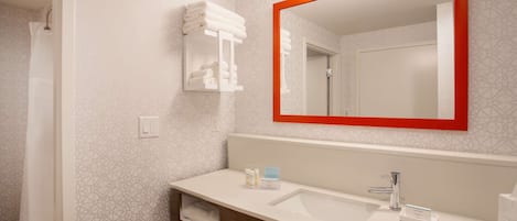 A modern bathroom with a white sink, a mirror with a red frame, and a towel rack.