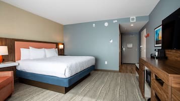 Une chambre d’hôtel avec un lit, un bureau doté d’une lampe, une télévision et une commode en bois.