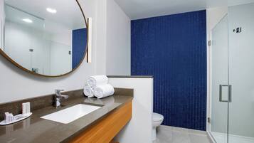 A modern bathroom with a large mirror, a sink, and a shower area.