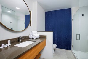 Bathroom features a large mirror, marble countertop, and glass shower enclosure.