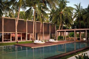 A modern pool area with lounge chairs, a pool, and palm trees.