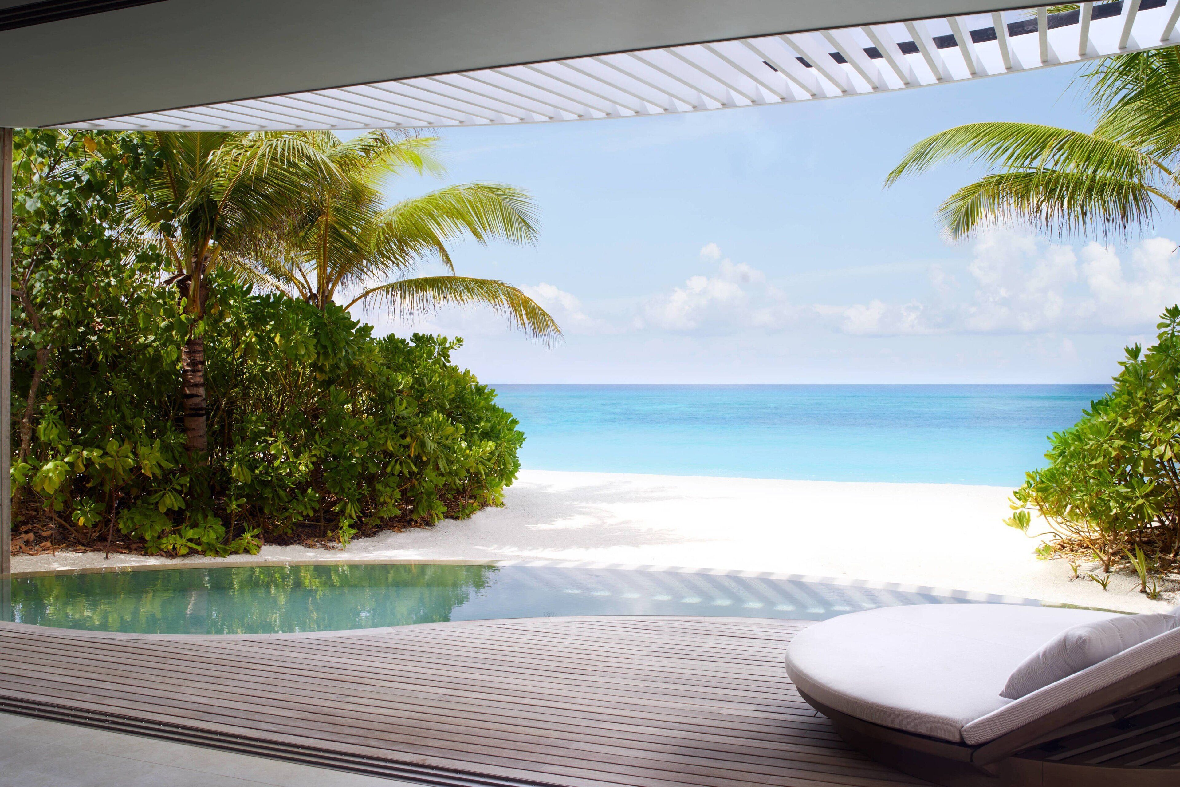 A poolside area with a view of a beach and ocean.