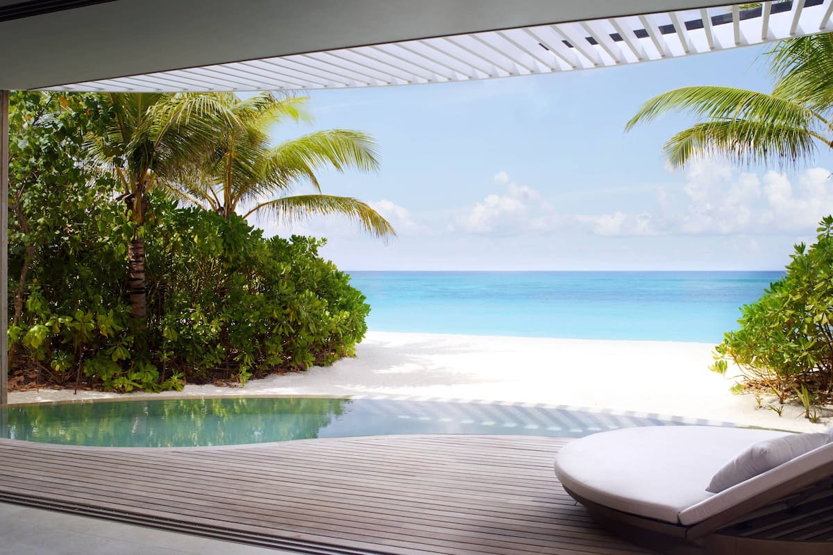 A poolside area with a view of a beach and ocean.
