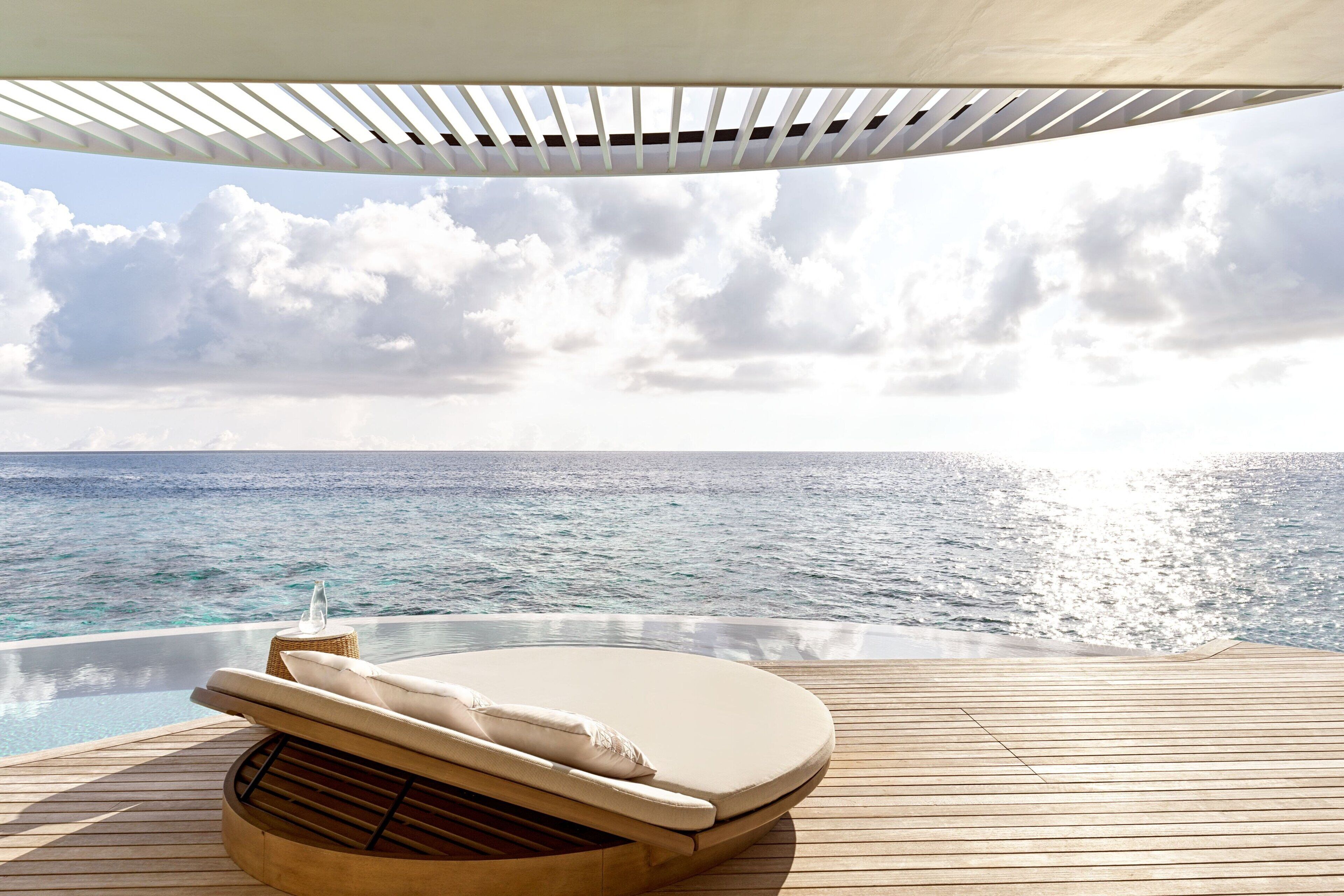 A sun lounger with a view of the ocean and a wooden deck.