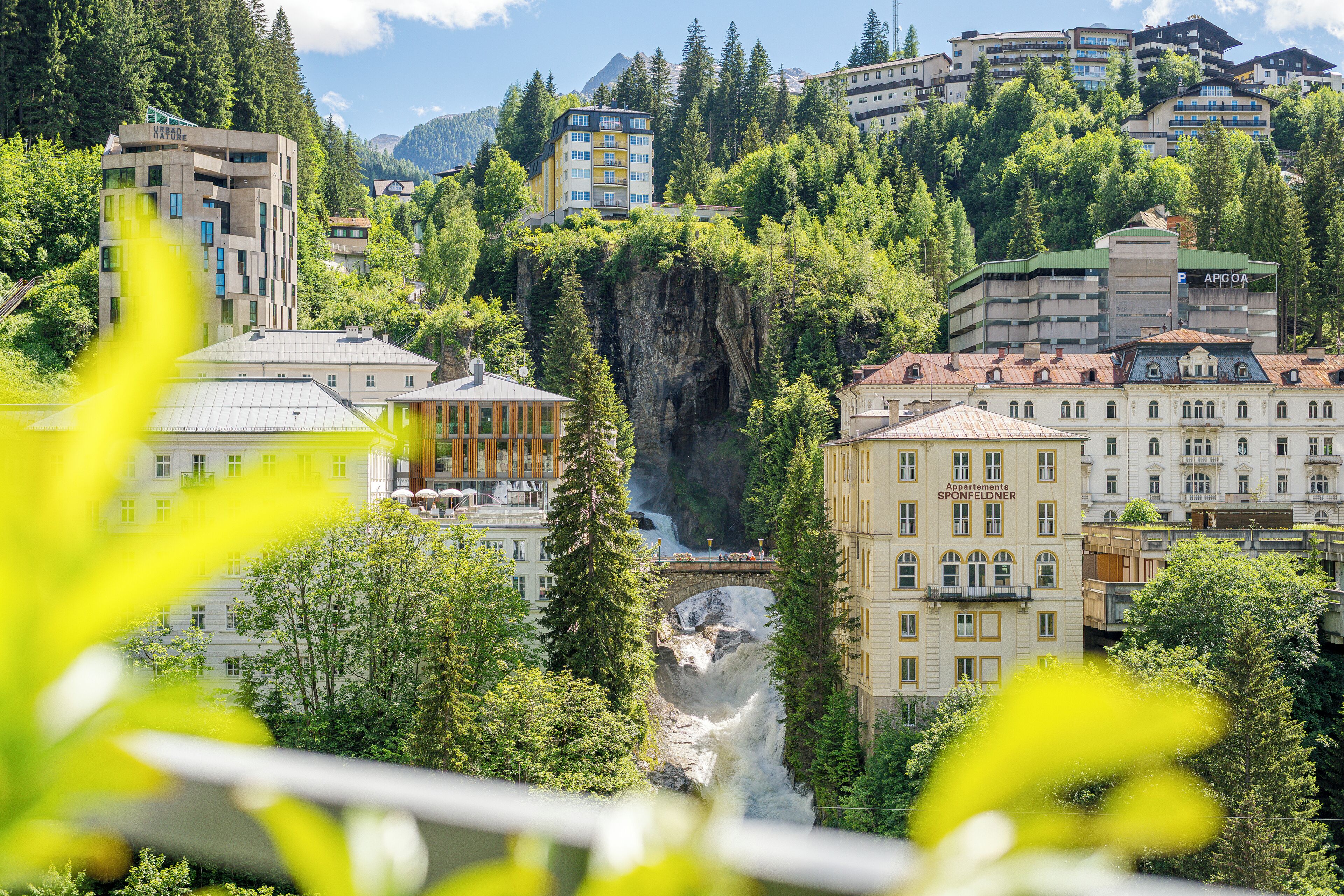 Un paisaje urbano con edificios, un puente y una cascada.