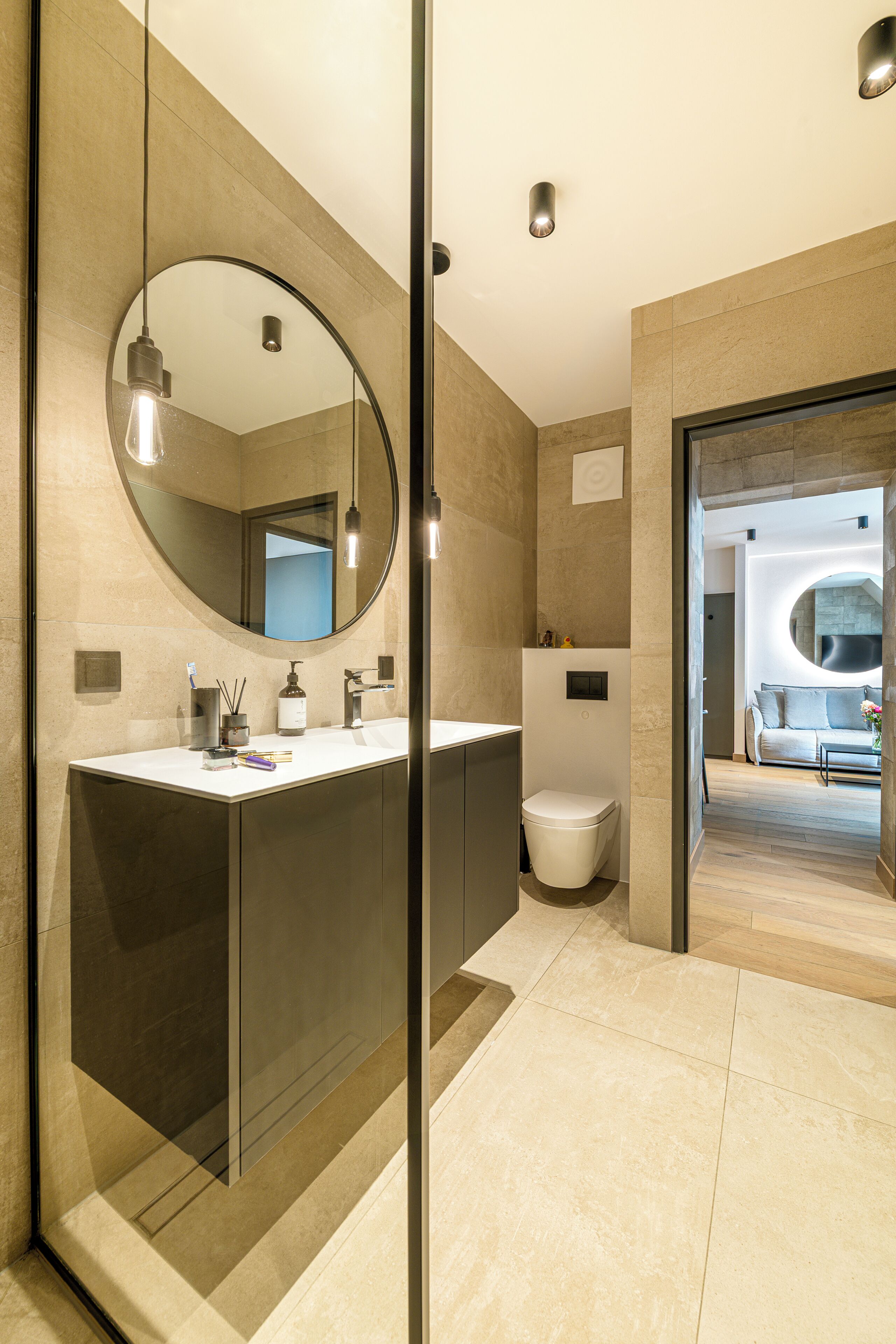 Un baño moderno con un espejo grande, un lavamanos y un inodoro.